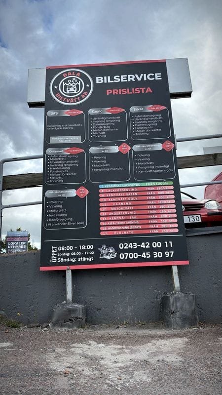 Dala Biltvätts skylt Bilservice prislista vid infarten, med priser, öppettider och telefonnummer.