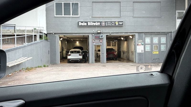 Dala Biltvätts lokal sedd från förarplatsen i en bil, med tvätthallens portar öppna.