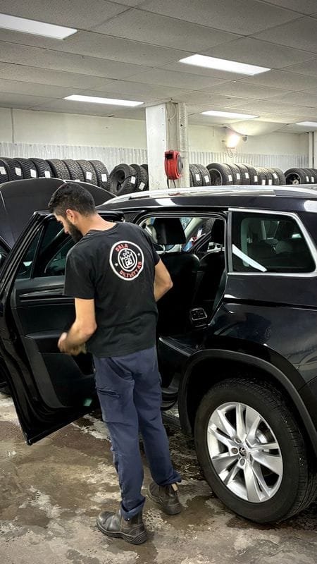 En medarbetare torkar av insidan av dörren på en svart SUV.